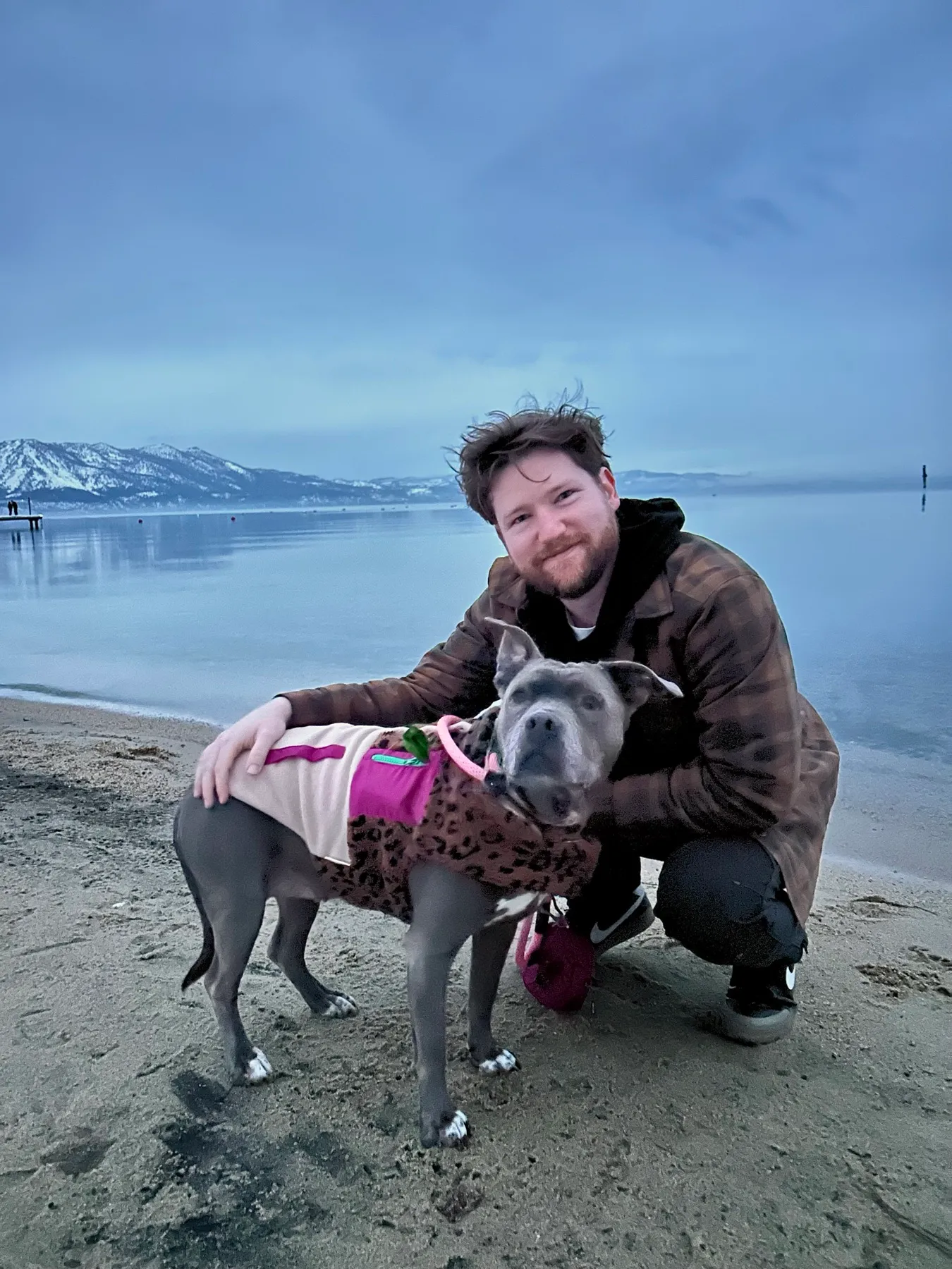 Zachary and his dog Boulder at the lakeshore, snowy mountains behind them